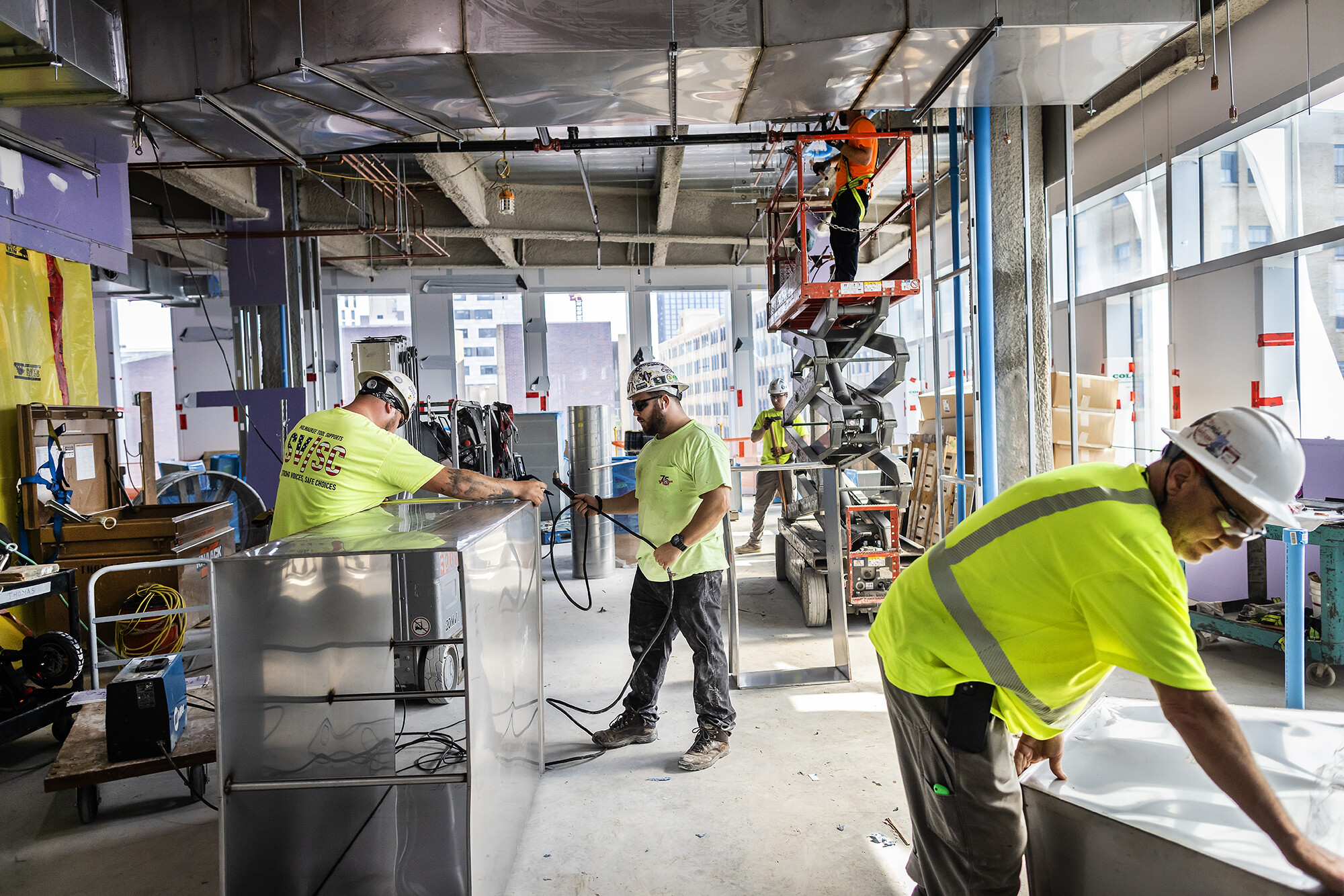 Interior construction progress with crew installing MEP systems